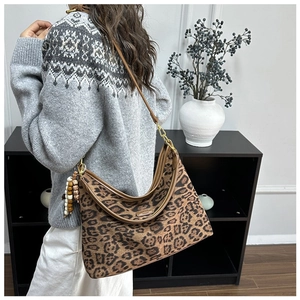 Detail der Vintage-Schultertasche mit Leopardenmuster, Perlenanhänger und Lederriemen