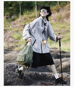 Outdoor action shot of grey windbreaker jacket and green canvas backpack for hiking