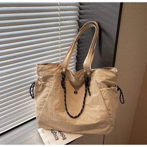 Dettaglio borsa tote in tela beige con accenti in corda intrecciata e tasche laterali