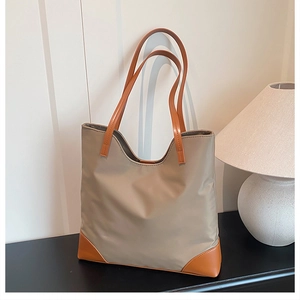 Detail of khaki tote bag with brown leather handles and reinforced base in a cozy room