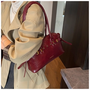 Detail of burgundy tote bag with vintage texture and golden hardware on trench coat