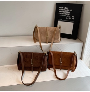 Detailed view of suede crossbody bags with vintage gold buckles on stone steps