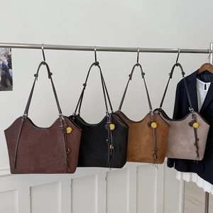 Four vintage tote bags in coffee, black, caramel, and taupe with furry ball pendants