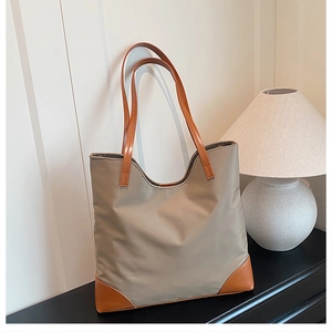 Close-up of khaki tote bag featuring brown leather trim and spacious interior design