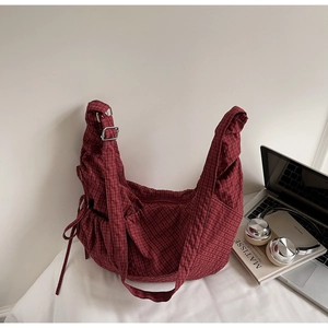 Detail of red checkered canvas hobo bag with side drawstring bows and adjustable strap