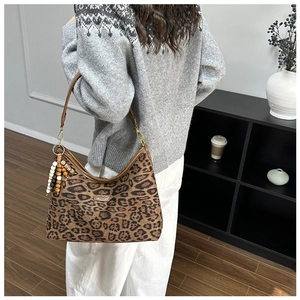 Detail der Hobo-Tasche mit Leopardenmuster, braunem Lederriemen und Perlenanhänger am Model