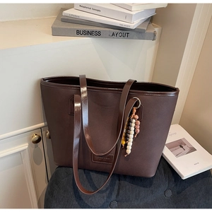 Détail du sac cabas en toile avec garniture en cuir brillant et pompon en perles