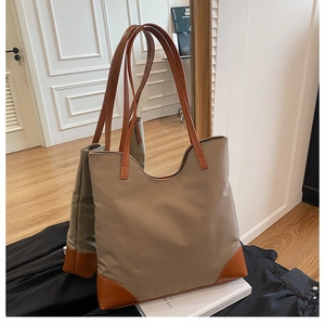 Detail of khaki nylon tote bag with brown leather handles and base protection