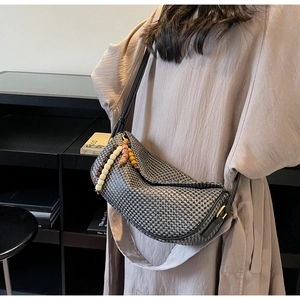Detail view of woven dumpling bag with monochromatic texture and beaded tassel