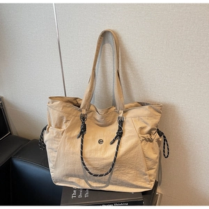 Dettaglio della borsa tote in tela beige con manici decorativi in corda intrecciata bicolore