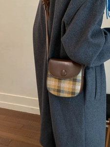 Retro brown leather saddle bag with green plaid wool fabric on female model