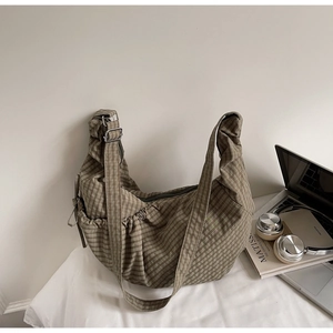 Detail of green checkered canvas hobo bag showing drawstring pocket and adjustable strap
