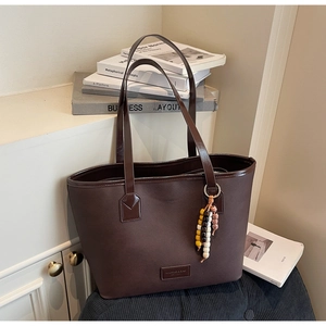 Détail du sac cabas marron foncé texturé avec logo de marque et accessoire de perles colorées
