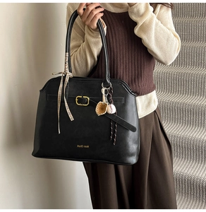 Detail of black suede tote bag featuring a gold buckle and plaid silk handle scarf