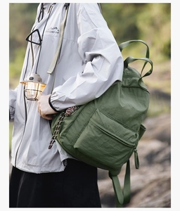 Detailed view of dark green nylon outdoor backpack with side pockets and large zipper front pouch