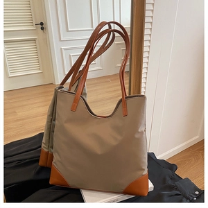 Detail of a khaki nylon tote bag with brown faux leather handles in a mirror reflection
