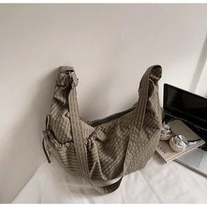 Detailed close-up of brown checkered canvas bag with drawstring side bow and wide strap