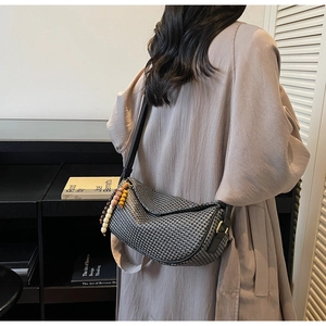 Detail of half-moon pleated shoulder bag with chic wooden bead charm and woven texture