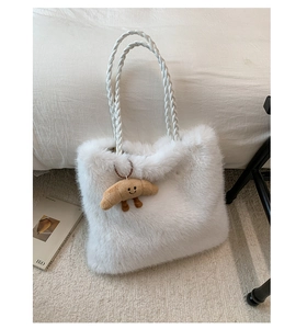 Detail of white fluffy faux fur tote bag with braided handles and a cute croissant pendant