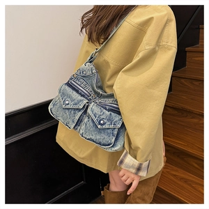 Détail du sac bandoulière en denim bleu avec poches multiples et rivets argentés chic