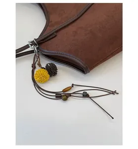 Detail of vintage brown suede tote bag with decorative tassel and wooden beads
