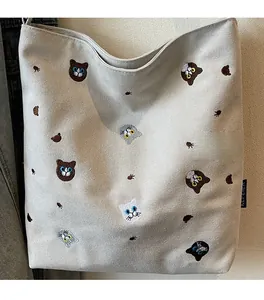 Detailed view of the cat head embroidery on thick beige canvas tote bag