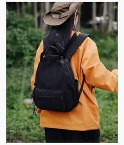 Outdoor shot of a black nylon backpack with a yellow jacket for daily commuting
