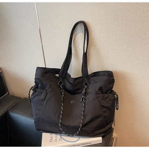 Dettaglio di una borsa tote grande in nylon nero con coulisse laterali regolabili