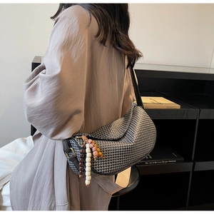 Close-up of houndstooth crossbody bag featuring wooden beads and tassel charms