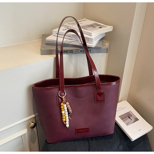 Vue détaillée du sac cabas bordeaux avec texture et breloque en perles de bois
