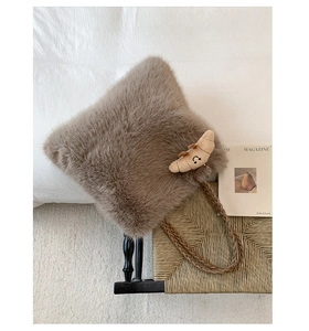 Close-up of brown plush faux fur tote bag with woven shoulder strap and croissant charm