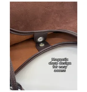Detail view of the secure magnetic snap closure on a brown vintage leather tote bag