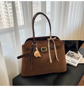 Brown suede tote bag detail with decorative silk scarf and leather bear charm on leather seat