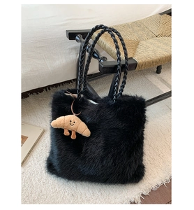 Detail of black faux fur tote bag with woven handles and cute plush croissant charm