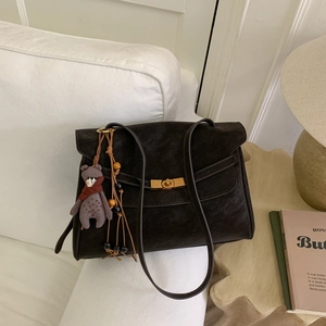 Detail of dark brown vintage bag with gold twist lock, bear charm and woven tassel