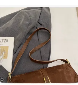 Detail view of dark coffee suede crossbody bag with premium gold metallic buckle