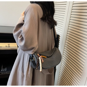 Back view of a woven dumpling bag with colorful beads and black PU leather strap