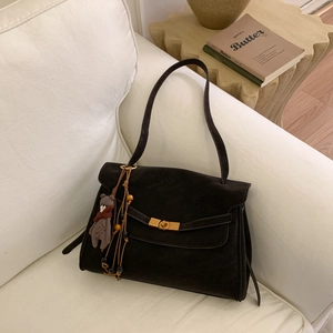Detail of dark brown suede tote bag with golden twist lock and teddy bear charm accessory