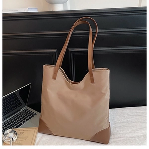 Detail of khaki nylon tote bag with brown leather reinforcement on corners and handles