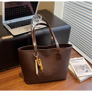Vue détaillée d'un grand sac cabas marron en tissu avec anses en cuir et bijou de sac