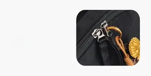 Detail of smooth metal double zippers and sunflower pendant on black nylon backpack