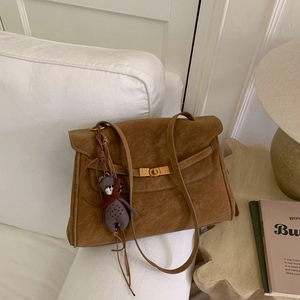 Detail of vintage brown shoulder bag with gold twist lock and a cute plush bear pendant