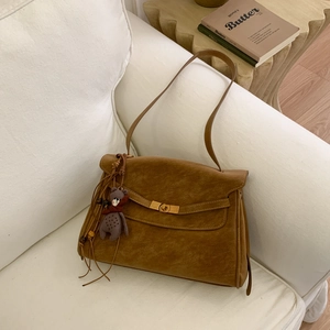 Detailed view of vintage brown suede handbag with golden clasp and cute bear charm