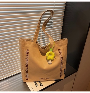 Detail of khaki canvas tote bag with Life text and yellow flower plush charm