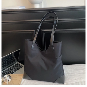 Minimalist black nylon tote bag showing its spacious capacity for laptops and headphones