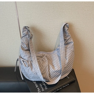 Close-up of crescent-shaped plaid canvas shoulder bag with decorative drawstring detail