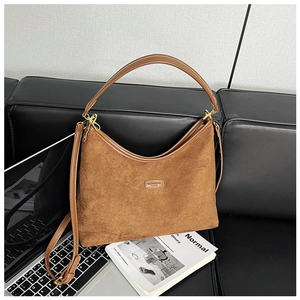Detailaufnahme der braunen Wildledertasche auf Ledersofa mit metallischen Elementen