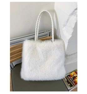 Detailed view of large white faux fur tote bag with braided leather straps on green chair