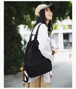 Side view of black nylon backpack with a decorative yellow tassel and wooden bead charm