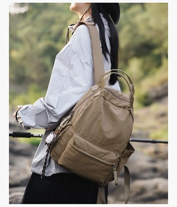 Outdoor shot of a khaki nylon backpack with owl charm and large capacity for students